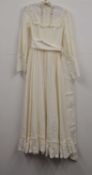 A c.1970's Laura Ashley dress, the full length cream cotton dress with high neck with lace trim, bib