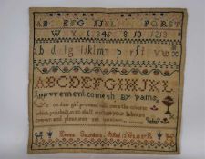 An early 19th century sampler, with polychrome alphabet and numerals, separated by decorative