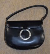 A black leather bag by Loewe, with saddlebag shape and foldover flap with metal ring closure,