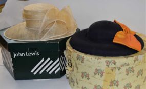 A navy blue and orange silk hat by Joan Biggs, together with a cream straw hat by John Lewis