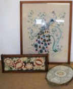 A needlework picture of a peacock, together with a table top bookshelf with needlework panel and