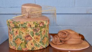 A cotton tapestry covered hat box together with a blush pink shot silk hat and a beige straw hat