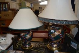 A near pair of patterned terracotta lamps with brass bases and cream shades