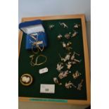 Display frame containing various white metal charms and other items