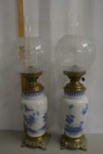 A pair of vase formed oil lamps with brass mounts and frosted glass shades with additional frosted