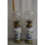 A pair of vase formed oil lamps with brass mounts and frosted glass shades with additional frosted
