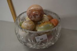 Cut glass bowl containing polished stone eggs and other items