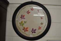 A circular framed study of vines painted on fabric