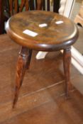 Small circular top milking stool on turned legs