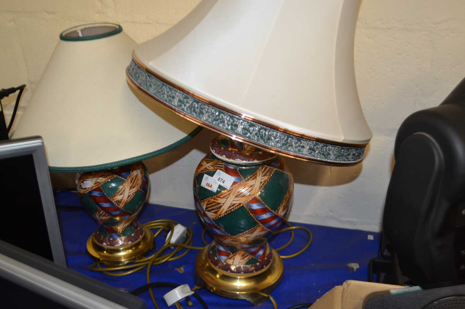 A near pair of patterned terracotta lamps with brass bases and cream shades