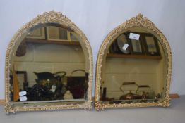 A pair of small dome topped bevelled mirrors with floral decorated frames, 38cm high