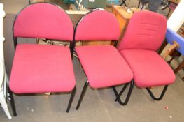 Three red upholstered office chairs