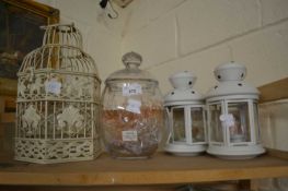 A pair of white candle lanterns together with a cream painted miniature bird cage and a glass