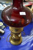 A Cranberry glass and brass oil lamp converted for electricity