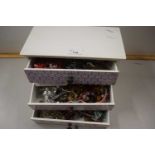 Small three drawer table top cabinet filled with costume jewellery