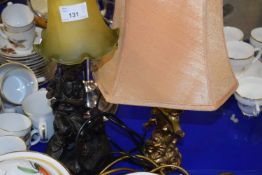 A bronzed resin figural table lamp withh frosted glass shade together with a further cherub based