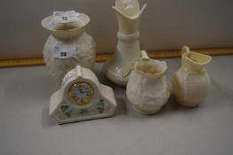 Collection of Belleek porcelain wares comprising three jugs, a mantel clock and vase