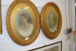 Pair of early 20th Century photographic portrait prints of a young couple set in oval floral