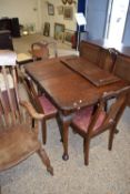 An early 20th Century walnut veneered dining room suite comprising and extending table, four