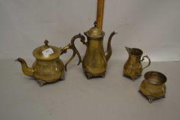 A brass teapot, coffee pot, milk jug and sugar bowl all raised on four stub feet with chased
