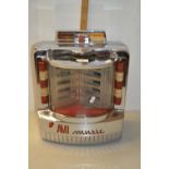 A vintage AMI Music wall mounted juke box in chrome case