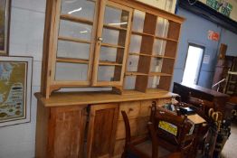 20th Century pine dresser cabinet of unusual form, the top with two glazed doors and shelved side