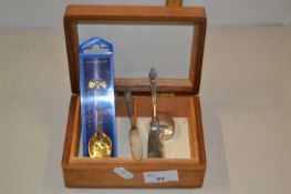 Wooden box together with a silver pill box, two butter knives and a commemorative spoon