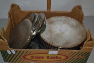 Box containing a quantity of table mats of various sizes covered with a white metal decoration