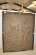 Oak framed pressed copper wall plaque depicting a jester and figures around a spinning wheel