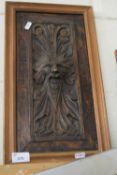 Carved wooden panel of a green man style face