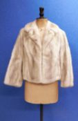 A lady's cropped fur jacket, with V-neck and single hook fastening slight lack of suppleness to