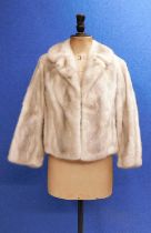 A lady's cropped fur jacket, with V-neck and single hook fastening slight lack of suppleness to