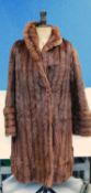 A lady's three quarter length Musquash fur coat by De Bella with hook fastening, deep cuffs and
