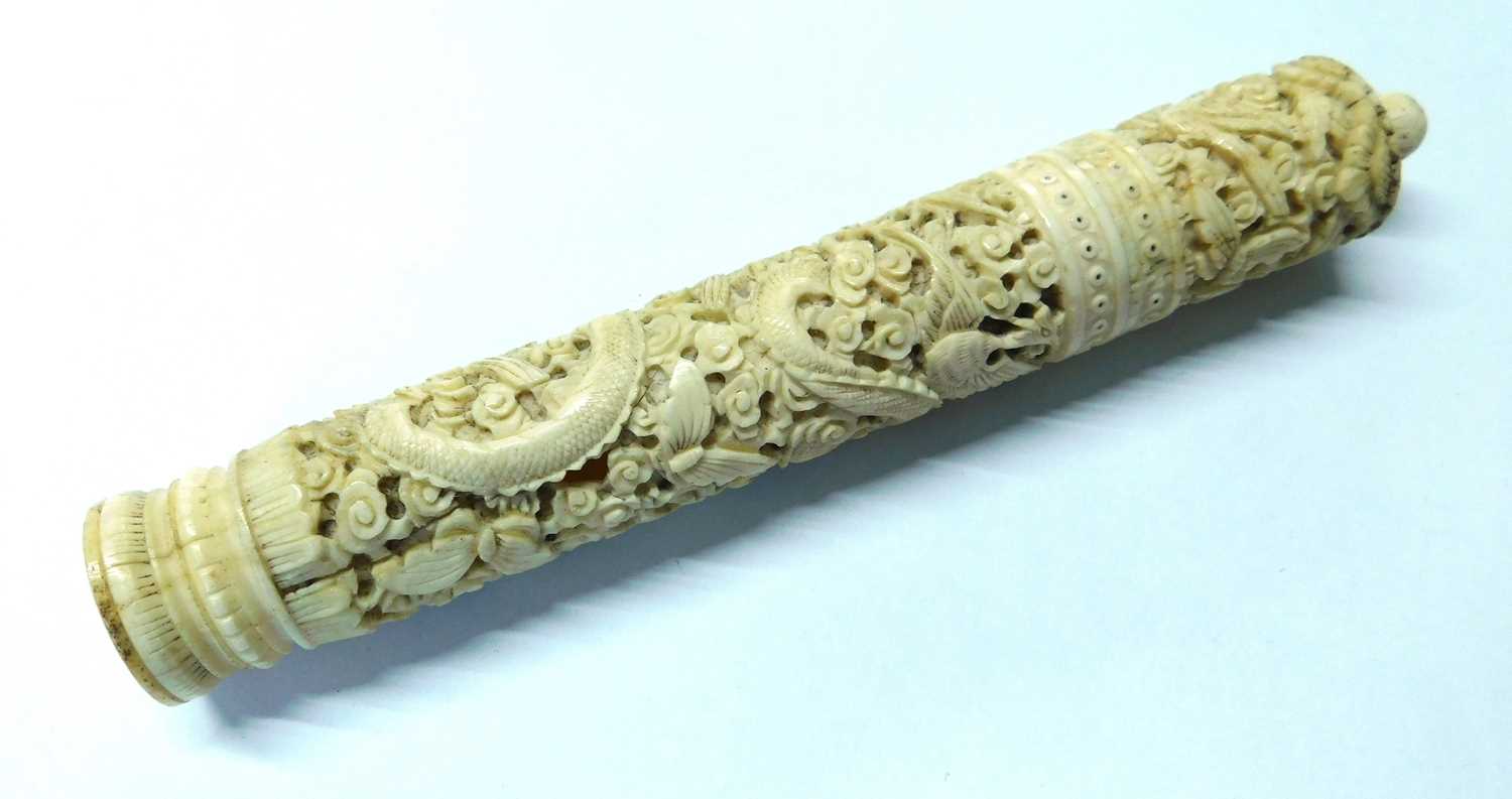 An Eastern carved bone needle case, the round case intricately carved with dragons, birds and