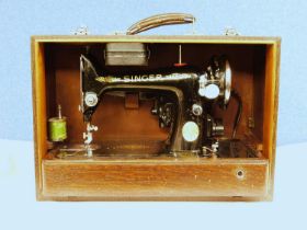 A c.1934 knee operated Singer sewing machine, cased with original cable and oil can