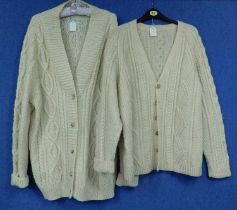 Two hand knitted cream woollen cardigans, one with horn buttons, the other with faux horn buttons (