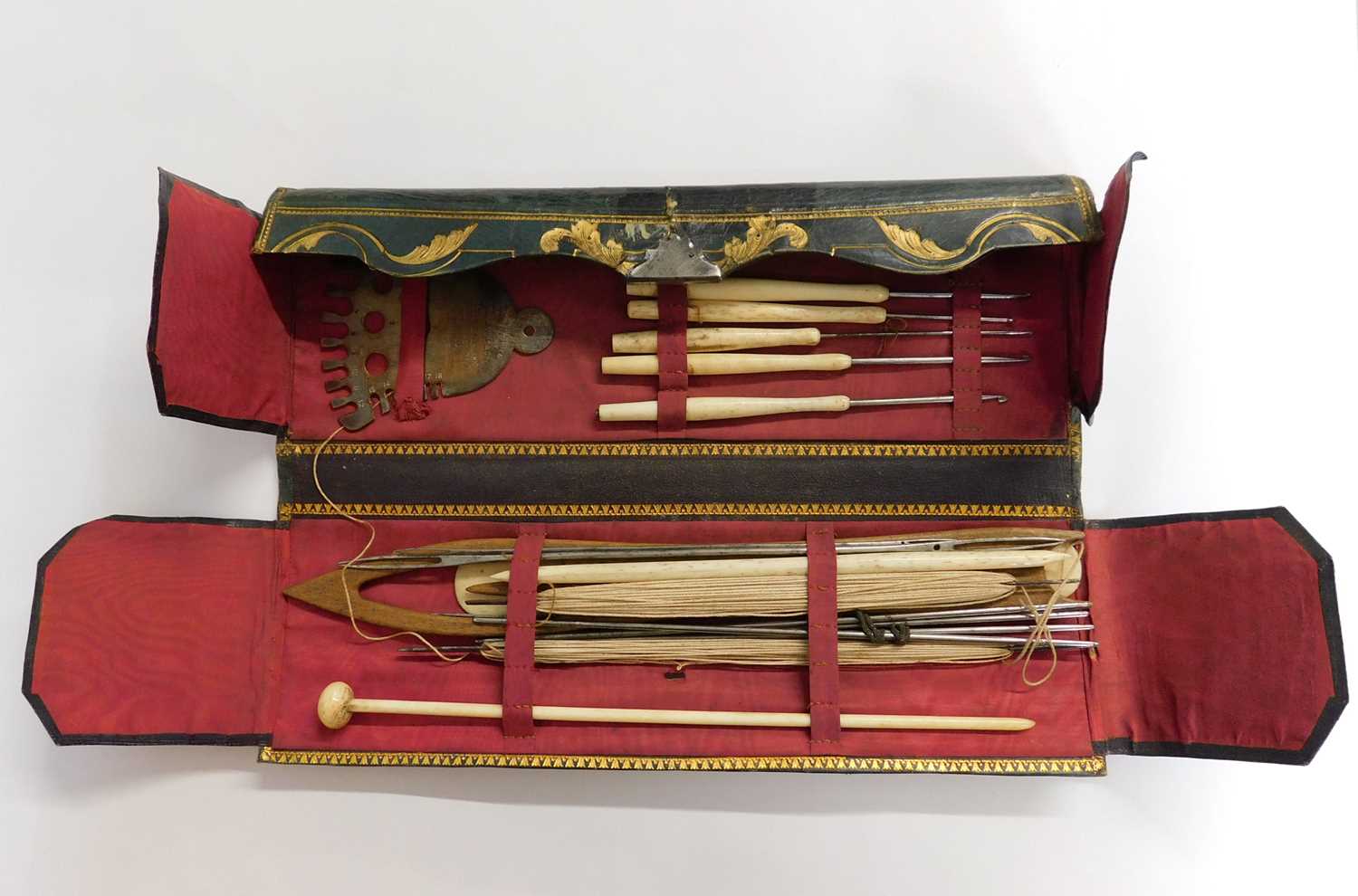 A leather case of various needlework tools, the green leather case with gilt decoration, opening