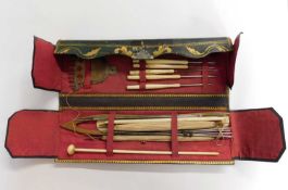 A leather case of various needlework tools, the green leather case with gilt decoration, opening