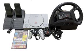A Playstation 1 console, together with: - Mad Catz steering wheel and foot pedals - Compatible