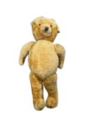 A large vintage teddy bear, straw stuffed, leather paw pads, stitched detail and growling mechanism.