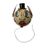 A vintage cardboard and wooden pull-string toy, formed as a face. Ears and tongue move/extend when