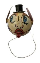 A vintage cardboard and wooden pull-string toy, formed as a face. Ears and tongue move/extend when