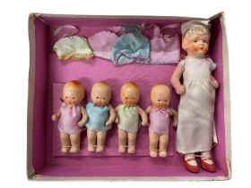 A boxed set of FOREIGN porcelain babies and nursery nurse, with original cloth clothing.