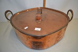 A large copper covered double handled cooking pan