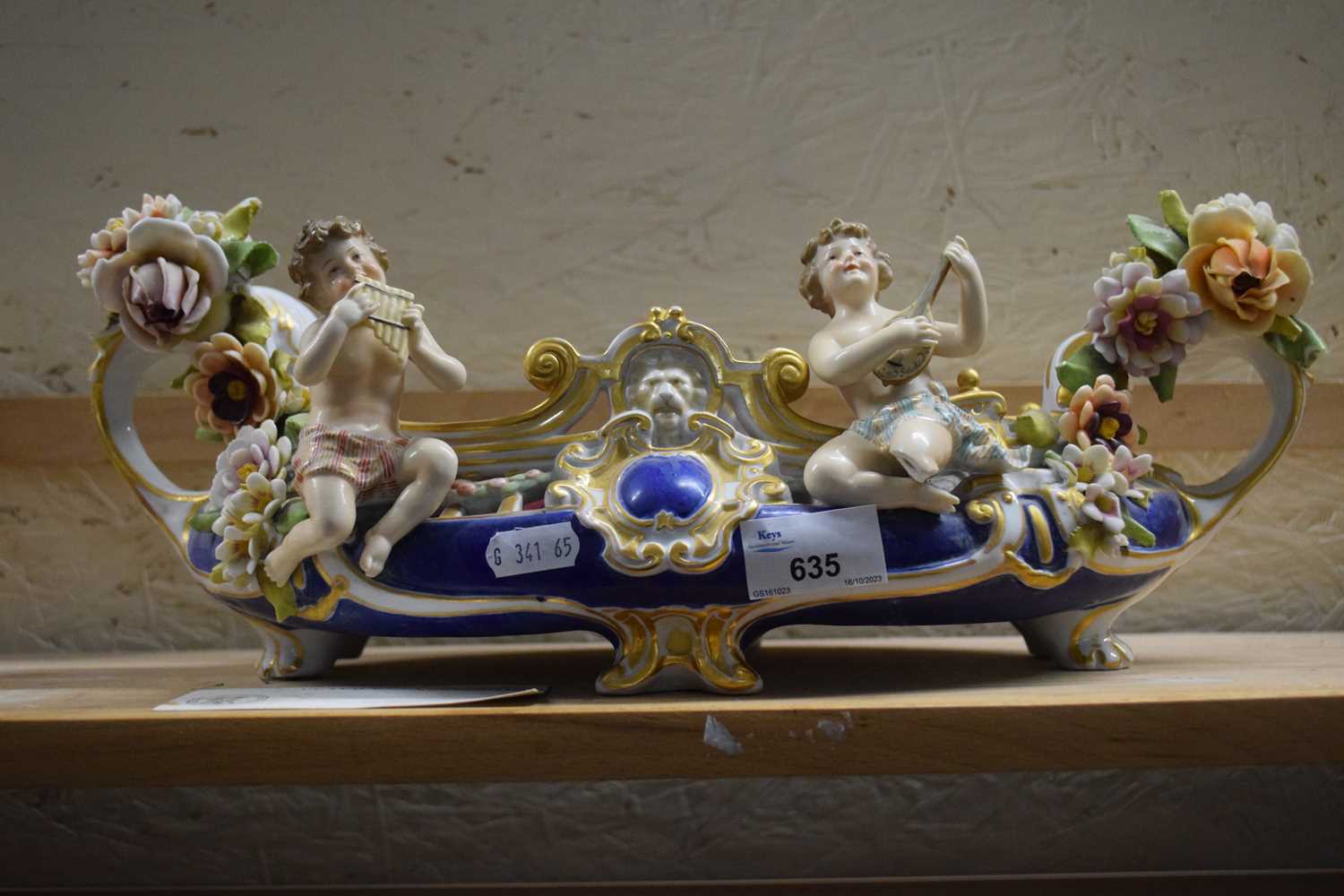 An ornate bowl with floral encrusted decoration and cherubs