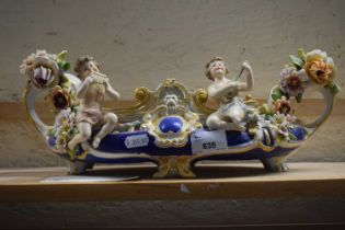 An ornate bowl with floral encrusted decoration and cherubs