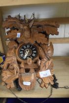 A large modern cuckoo clock with heavily carved face depicting a stags head