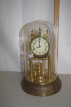 A brass anniversary clock set under a glass dome