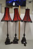 A set of three modern table lamps with red and black fabric shades and classical style metal bases