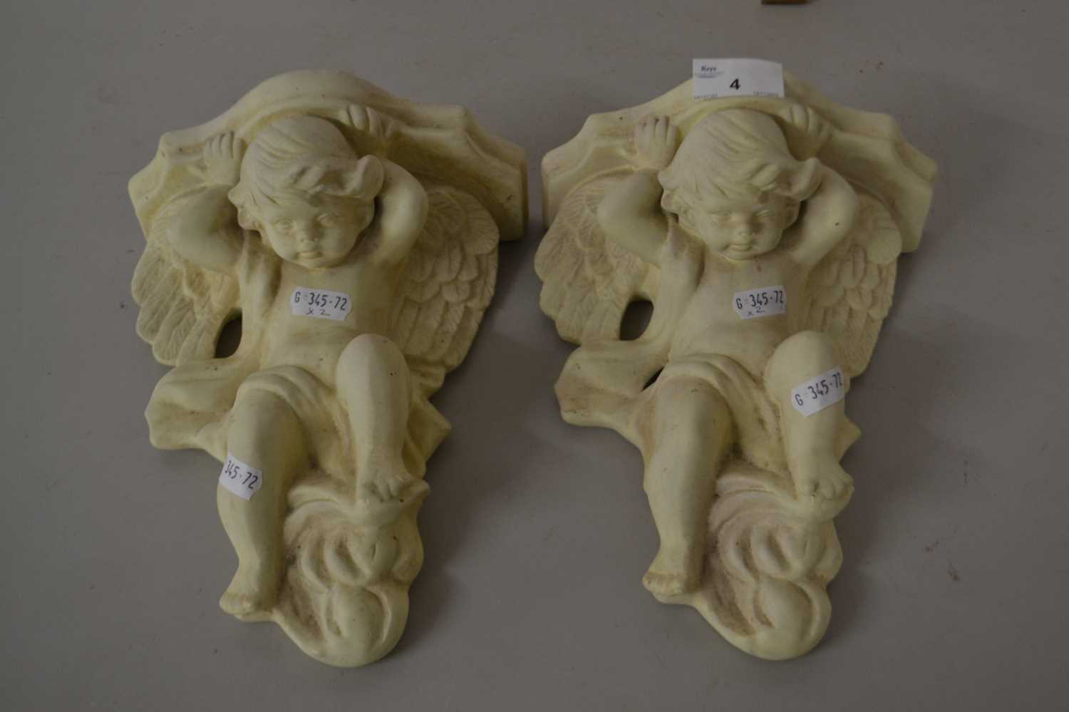 A pair of modern wall brackets decorated with cherubs